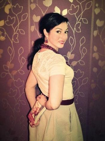 ©Dorothee Oelbracht Schwarzhaarige Frau im weißen Kleid vor einer Fototapete und einem Buch in der Hand