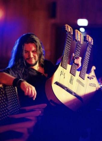 ©Jens Hedrich Mann mit langen Haaren und einem Musikinstrument in der Hand