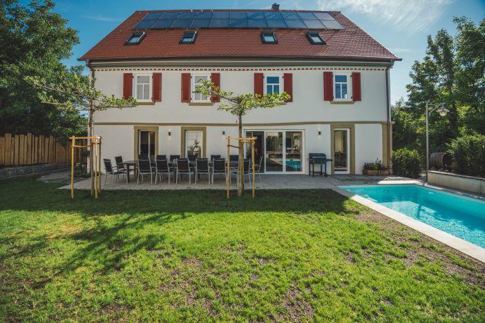 Rückansicht vom Haus mit Terrasse und Tisch, recht der Pool